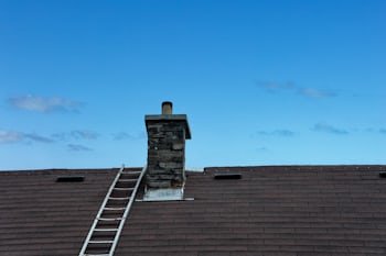 Chimney with a ladder set up for service, similar to homes throughout Mason, OH